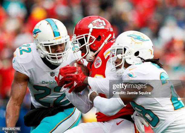 Wide receiver Tyreek Hill of the Kansas City Chiefs makes a catch as strong safety T.J. McDonald and cornerback Bobby McCain of the Miami Dolphins...