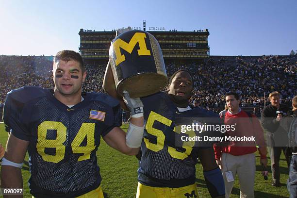 Tight end Shawn Thompson and linebacker Shantee Orr of the Michigan Wolverines hold the Little Brown Jug after winning the Big Ten Conference...