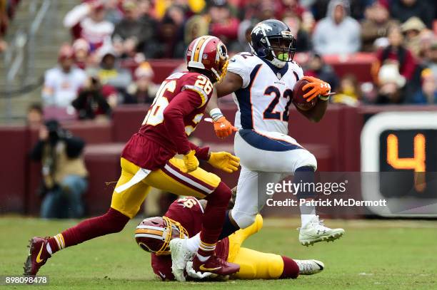 Running back C.J. Anderson of the Denver Broncos runs with the ball past outside linebacker Preston Smith and cornerback Bashaud Breeland of the...