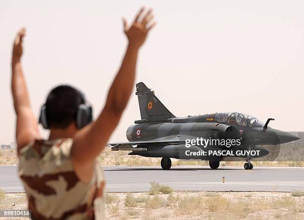 French soldier directs a Mirage 2000D back on the runway at the NATO base in Kandahar after a mission above Afghanistan on August 15, 2009. The...