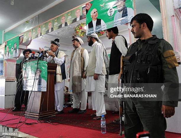 An Afghan policeman stands guard as presidential candidate Ashraf Ghani Ahmadzai addresses a gathering during an election campaign in Kandahar on...