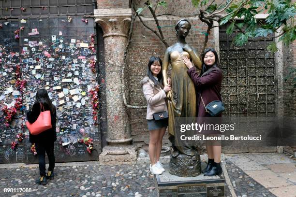 Tourists pose beside Juliet's statue in the courtyard of Via Cappello 23, which is today known as “Juliet’s House” on November 20, 2017 in Verona,...