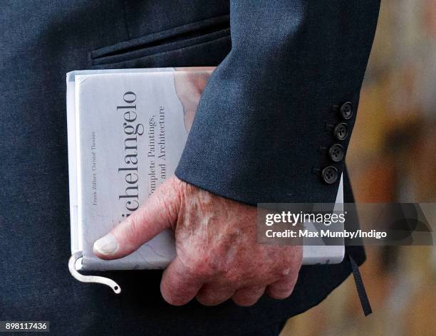 Prince Philip, Duke of Edinburgh carries his book 'Michelangelo: The Complete Paintings, Sculptures and Architecture' as he and Queen Elizabeth II...