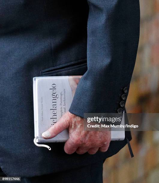 Prince Philip, Duke of Edinburgh carries his book 'Michelangelo: The Complete Paintings, Sculptures and Architecture' as he and Queen Elizabeth II...