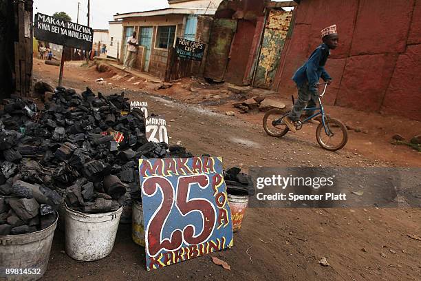 Child rides his bicycle past charcoal for sale in the Kibera slum August 15, 2009 in Nairobi, Kenya. The Kibera slum is home to roughly one million...