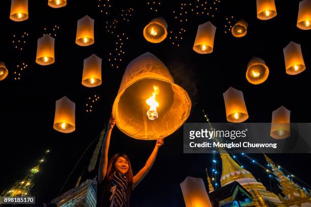 beautiful asian women release sky lanterns to worship buddha's relics in yi peng or yee peng festival at wat jongklang temple - wat jongkham temple in mae hong son near chiang mai, thailand. - chiang mai province stock pictures, royalty-free photos & images