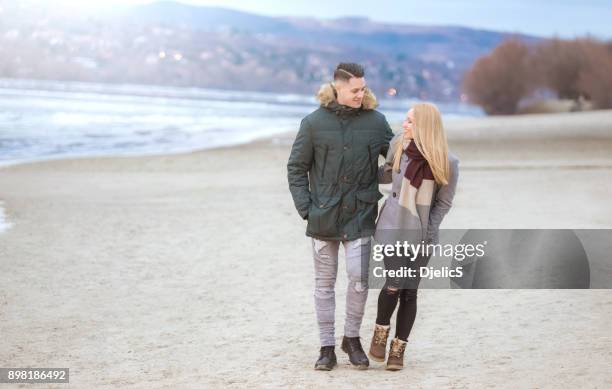 young happy couple walking next to danube river. - romantic couple walking winter beach stock pictures, royalty-free photos & images