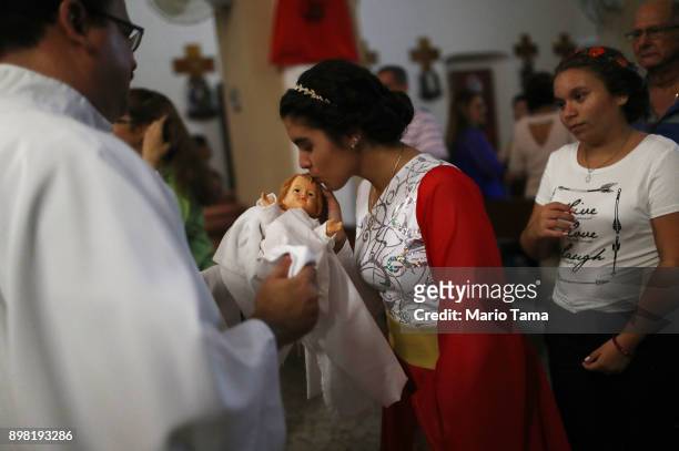 An altar server kisses a doll depicting Jesus Christ during 'midnight mass' at the Nuestra Senora Del Carmen Church on Christmas Eve on December 24,...
