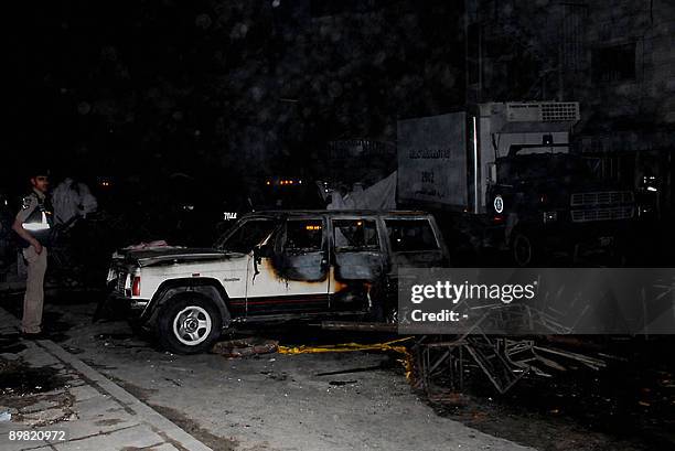 Kuwaiti policeman stands guard near a burnt vehicle after a fire ripped through a packed wedding party in Jahra, west of Kuwait City, early on August...