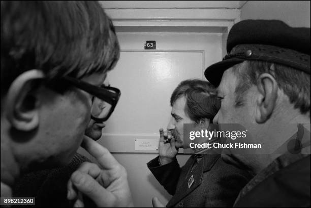 Polish trade-unionist Lech Walesa smokes a cigarette as he talks with unidentified others outside his office at Solidarity headquarters, Gdansk,...