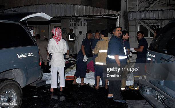 Kuwaiti rescue workers and security officials gather around the bodies of victims after a fire ripped through a packed wedding party in Jahra, west...