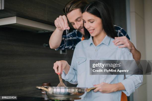 boyfriend adding salt to the pan while hugging his girlfriend - sprinkling salt stock pictures, royalty-free photos & images