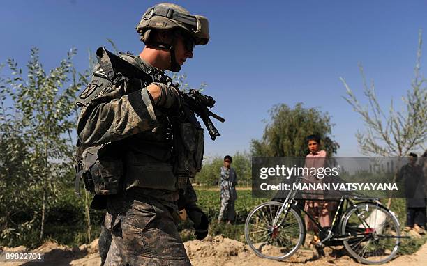 Soldier from the 2nd Platoon Alpha 3-71 cavalry walks past a group of children on the roadside during a patrol mission in the Baraki Barak district...