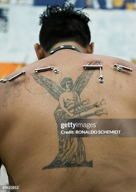 Tattoo artist Jorge Castro gets ready to be hung from piercing hooks on his back on August 15 in an attempt to set a Guinness record of a 3-hour...