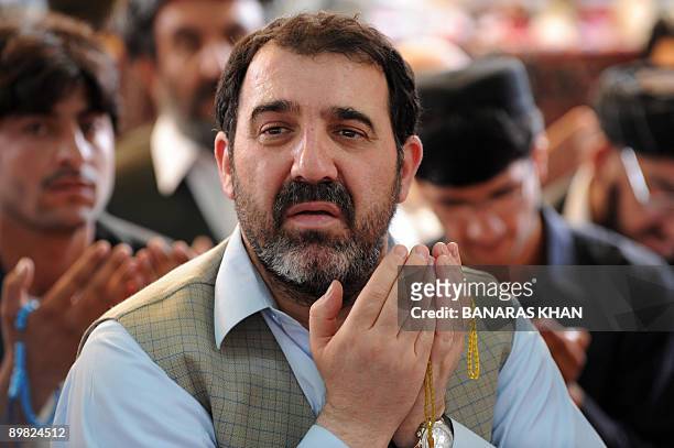 Ahmed Walli, brother of Afghan President Hamid Karzai, prays along with Karzai supporters at an election gathering in Kandahar on August 16, 2009....