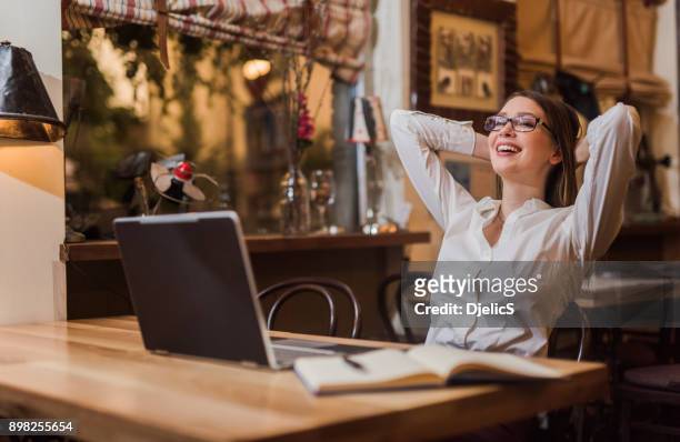 young woman feeling relieved after late night work is done. - relief emotion stock pictures, royalty-free photos & images