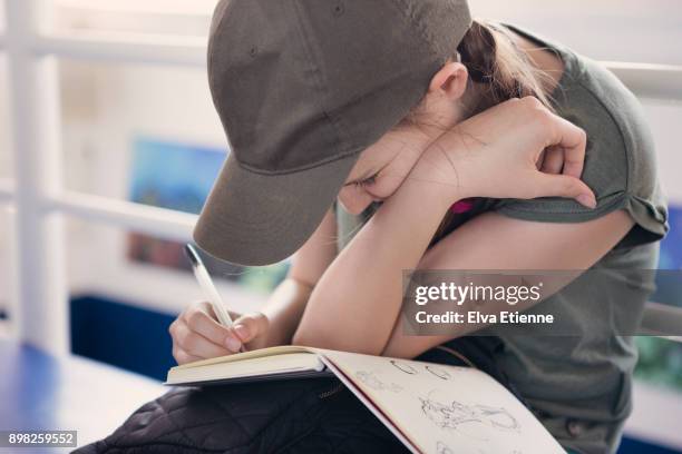 bored teenager sketching in a notebook - baseball cap stock pictures, royalty-free photos & images