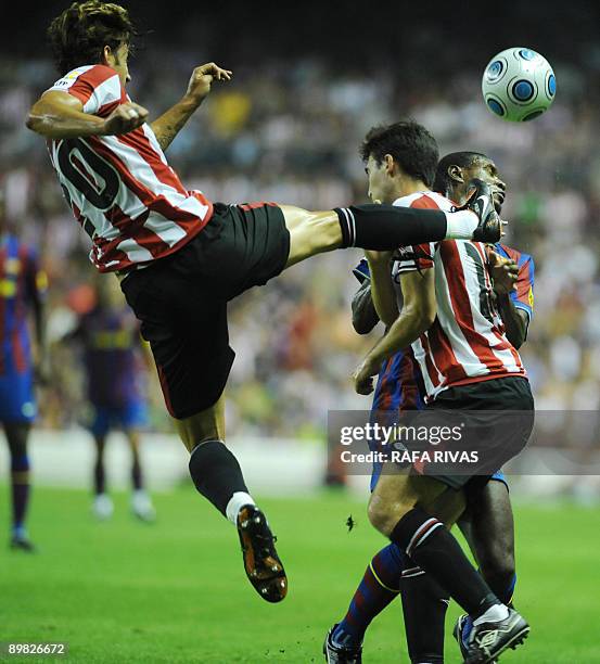 Athletic Bilbao's Aitor Ocio kicks the ball next to teammate Andoni Iraola and Barcelona's French Eric Abidal during their Spanish Supercup 1st leg...