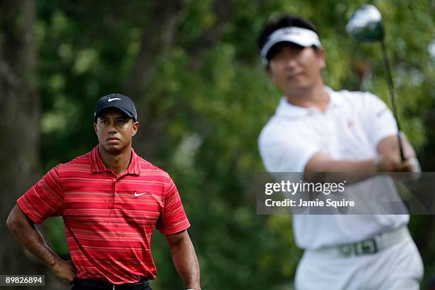 Yang of South Korea hits his tee shot on the ninth hole as Tiger Woods looks on during the final round of the 91st PGA Championship at Hazeltine...