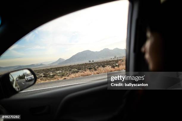 woman looking out car window - auto interieur stockfoto's en -beelden