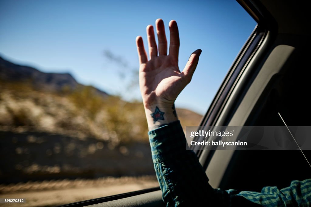 Man Holding Hand Out Car Window