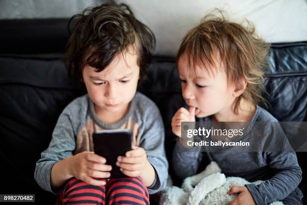 two boys looking at mobile phone - thumb sucking stock pictures, royalty-free photos & images