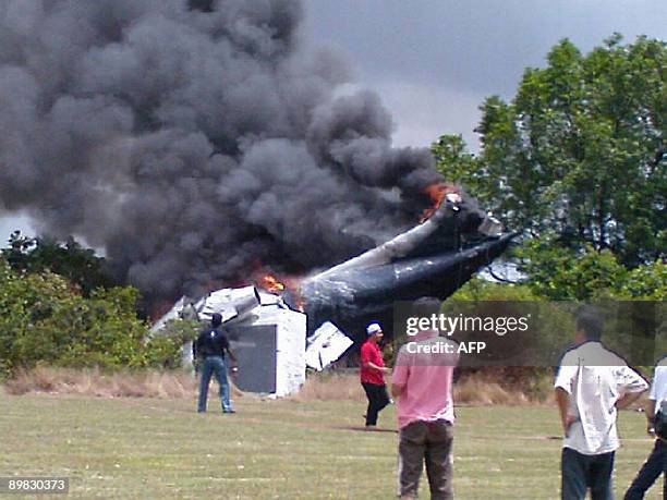 This picture taken on August 16, 2009 shows people looking at a burning plane which crashed during a test flight in Taiping, northern Perak State. A...