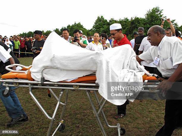 This picture taken on August 16, 2009 shows Malaysian rescue workers carrying away the body of British pilot Michael Robert Dacre from the site of a...