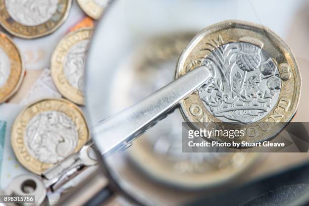 one pound coin under magnifying glass - british coin stock pictures, royalty-free photos & images