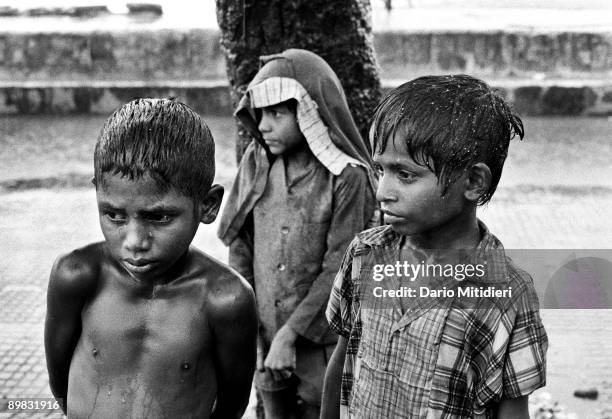 Street children sheltering from the monsoon rain on Chowpatti beach in Bombay, India.