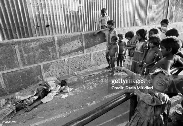 Group of pavement and street children gather around the body of a vagrant near Crawford Market in Bombay.