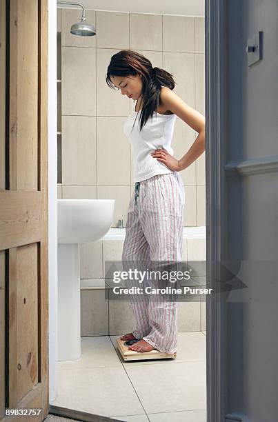 mixed-race young woman on bathroom scales - body image stock pictures, royalty-free photos & images