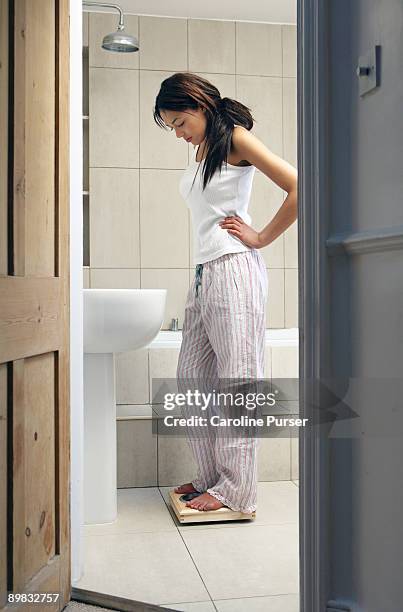 mixed-race young woman on bathroom scales - sad girl standing stock pictures, royalty-free photos & images