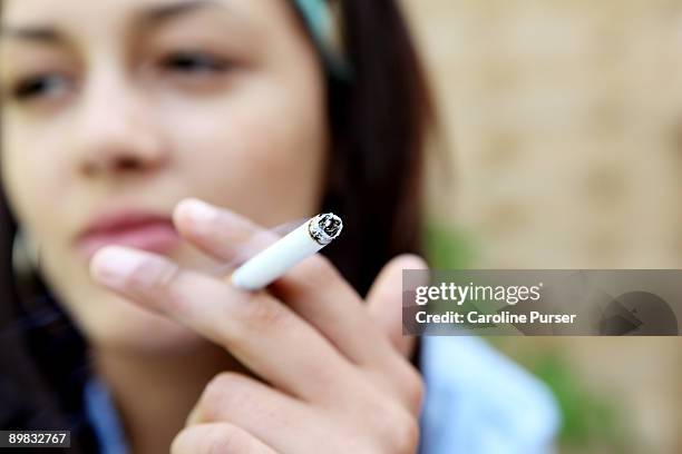 mixed-race young woman smoking a cigarette - produto relacionado com tabaco - fotografias e filmes do acervo