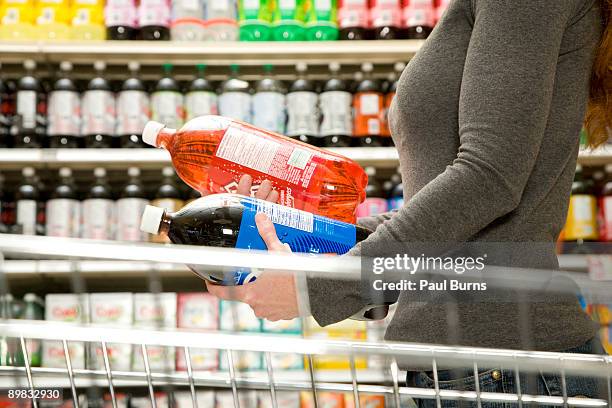 woman comparing ingredients on soda bottle - cold drink stock pictures, royalty-free photos & images