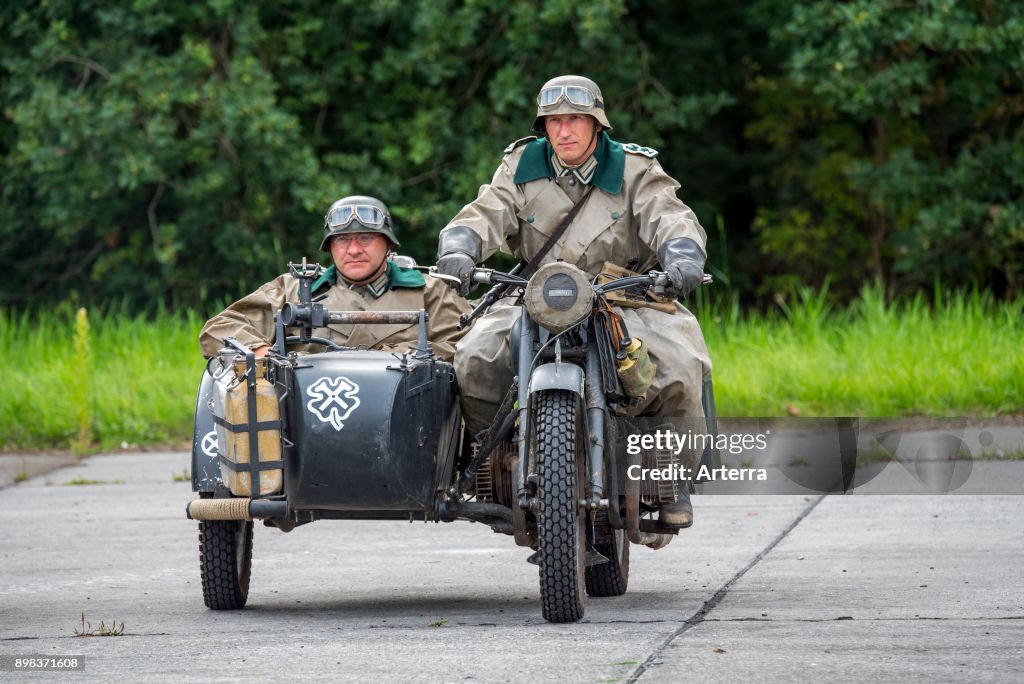 German WW2 soldiers riding on BMW military motorcycle with sidecar during World War Two re-enactment.