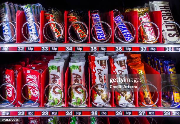 Snack vending machine / snack dispenser selling colourful sweets and chocolate bars in public place.