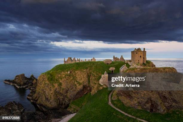 Menacing dark clouds above Dunnottar Castle, ruined medieval fortress near Stonehaven on cliff along the North Sea coast, Aberdeenshire, Scotland.