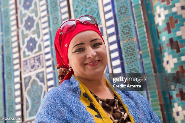 Uzbek musilim woman with gold teeth dressed in traditional dress with red headscarf in Samarkand, Uzbekistan.