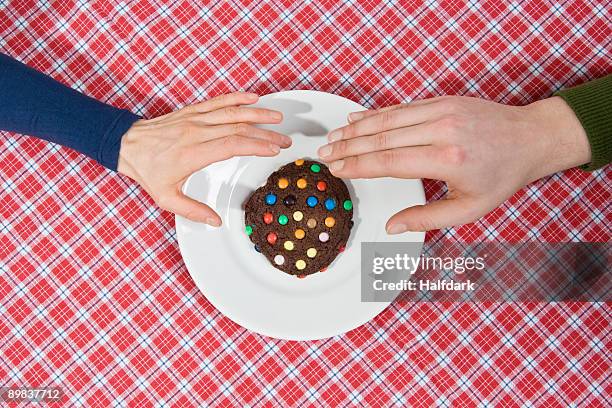 two hands reaching for a cookie - sharing chocolate stock-fotos und bilder