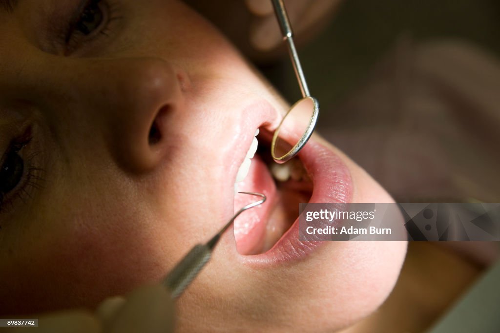 Close-up of a dentist inspecting a woman's mouth