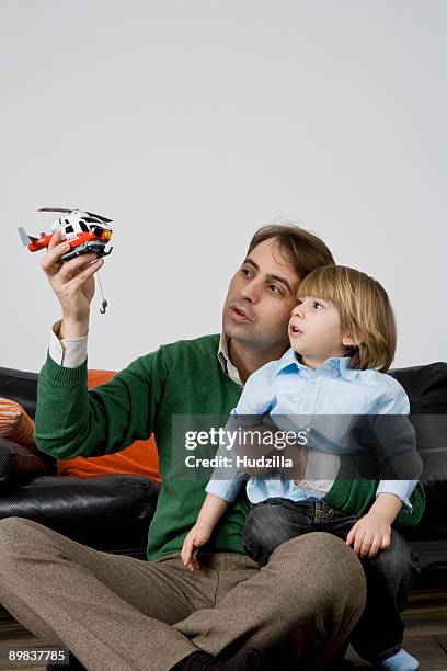 a father and son playing with a toy helicopter - toy helicopter stock pictures, royalty-free photos & images