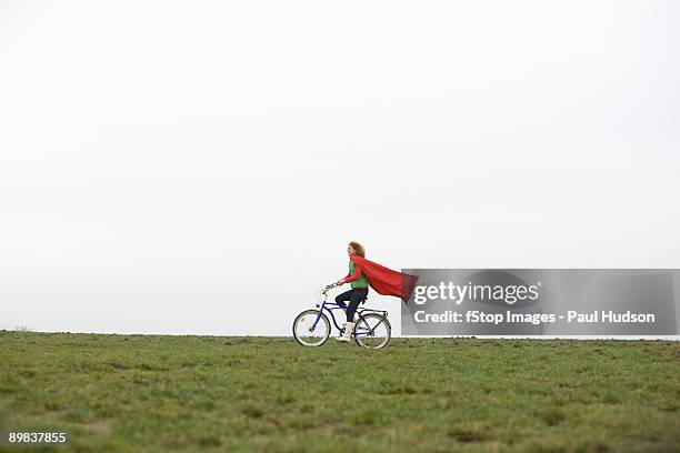 a woman riding a bike through a park - red riding boots stock pictures, royalty-free photos & images