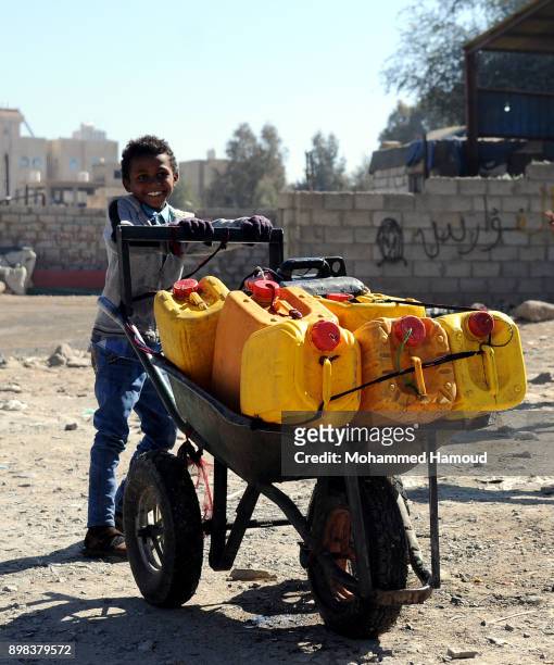 Boy pushes a wheelbarrow carrying jerry cans after he filled them with clean water from a charity water pump during a water shortage on December 22,...