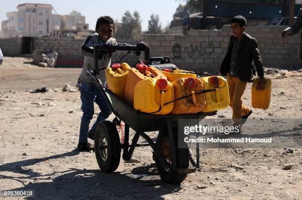 Boy pushes a wheelbarrow carrying jerry cans after he filled them with clean water from a charity water pump during a water shortage on December 22,...