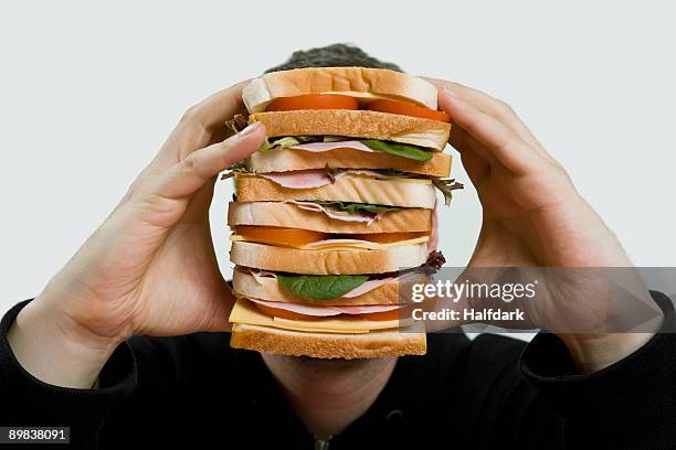 a man holding a large sandwich - vreten stockfoto's en -beelden