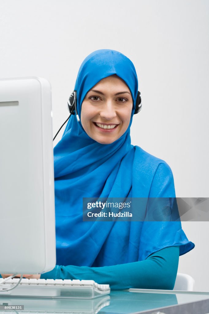 A woman wearing a Hijab and working in a call center