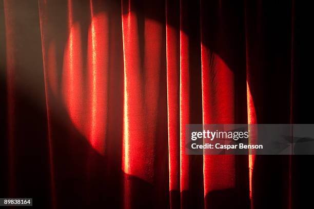 a spot lit red stage curtain - rideau de scène photos et images de collection