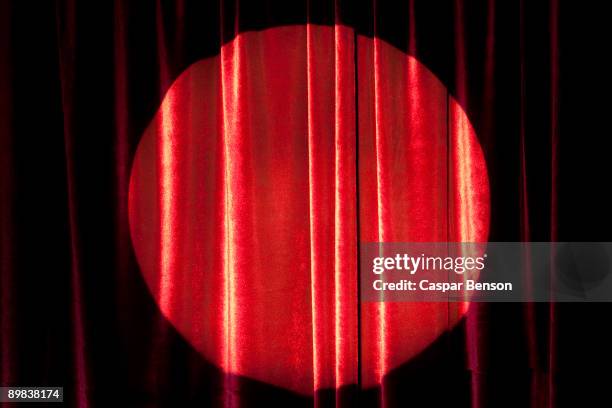 a spot lit red stage curtain - rideau de scène photos et images de collection