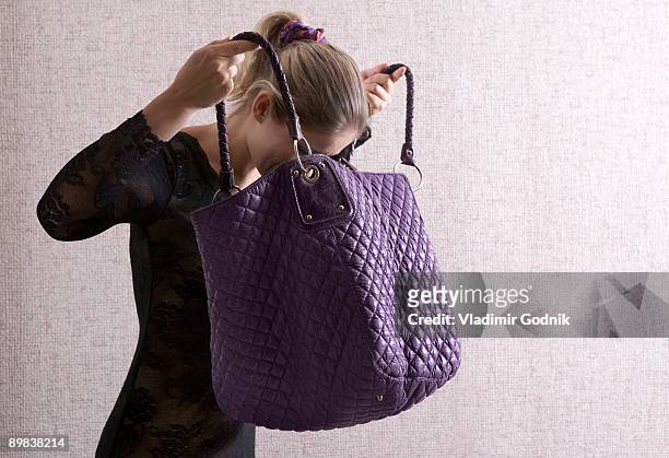 a woman looking into her large purse - handtasche stock-fotos und bilder